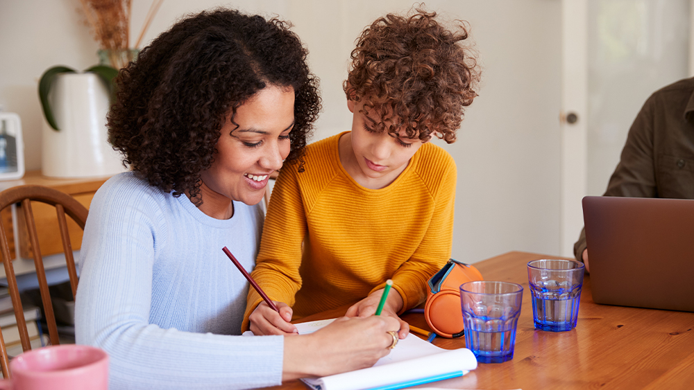Mother Helping Son With Homework On KitchenTable