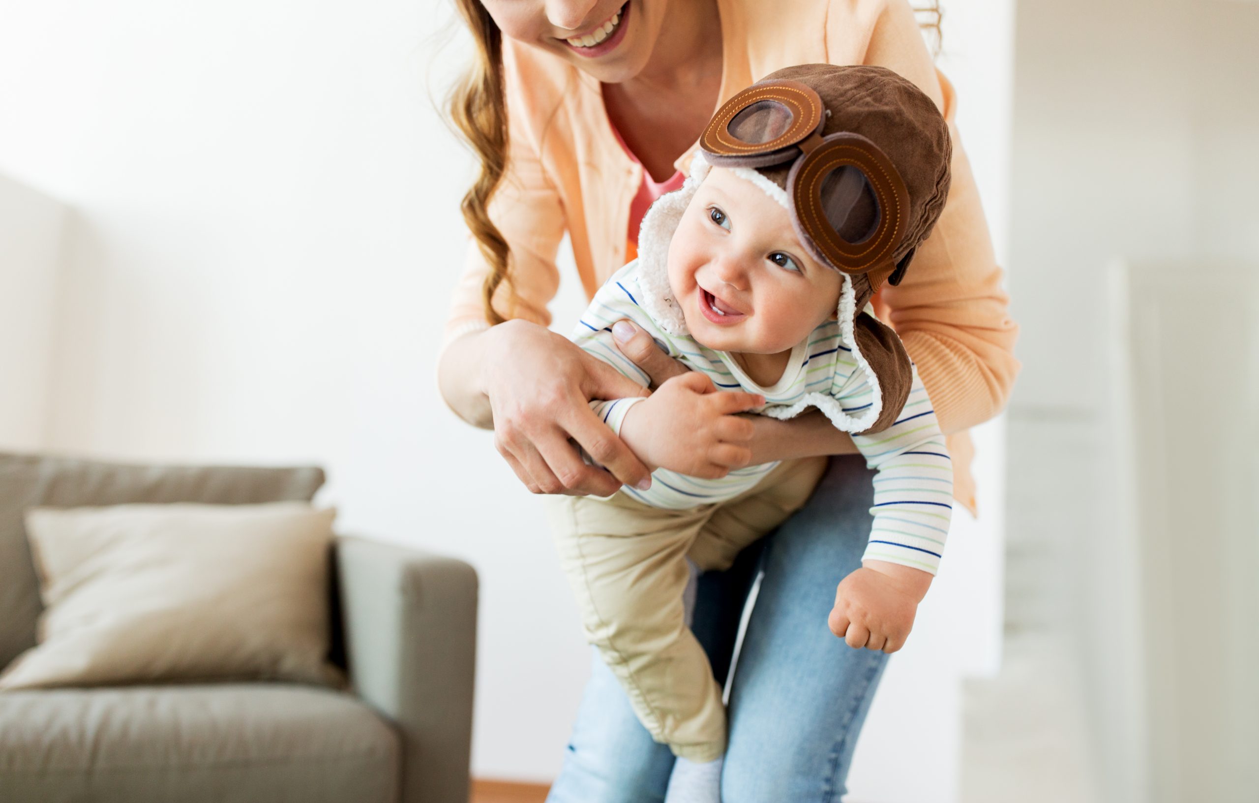 Mother with Baby Wearing Pilot Hat at Home