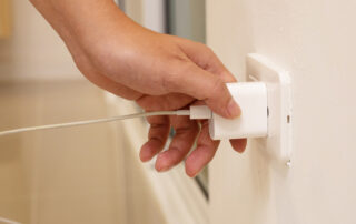 hand plugging into electrical outlet
